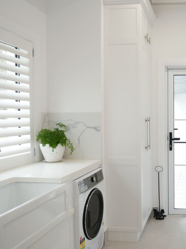 Laundry Cabinet Painting Modern white laundry room with shaker-style cabinets, marble splashback, and fresh cabinet painting for a clean, bright finish.