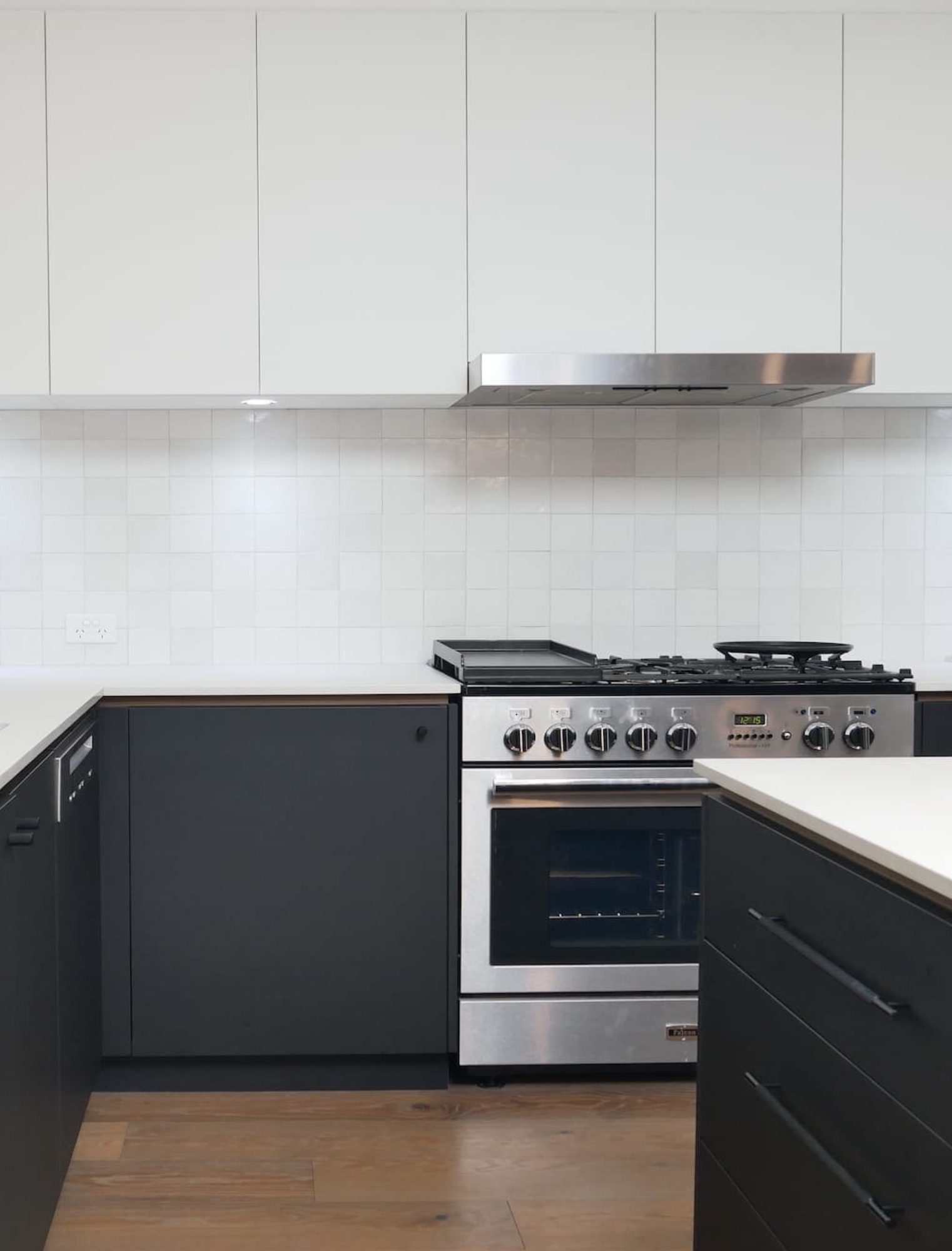 A modern black and white kitchen featuring sleek laminate cabinetry, contrasting light and dark finishes, and clean, minimalist design elements.