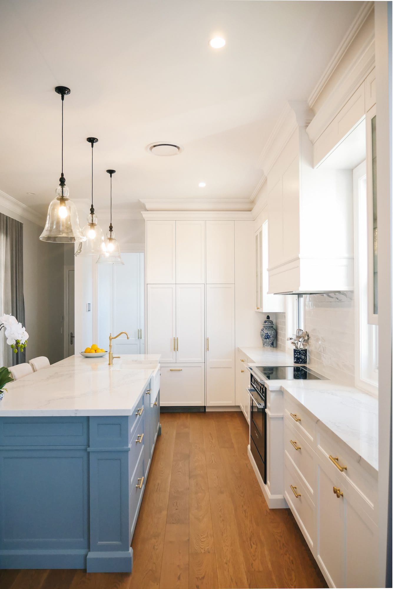 polyurethane kitchen island in blue surrounded by white cabinets with gold handles. 